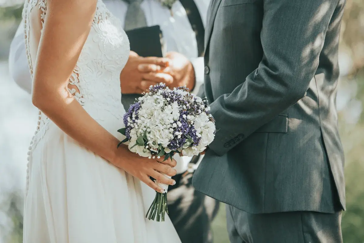 Couple exchanging vows beneath a floral arch in The Orangery